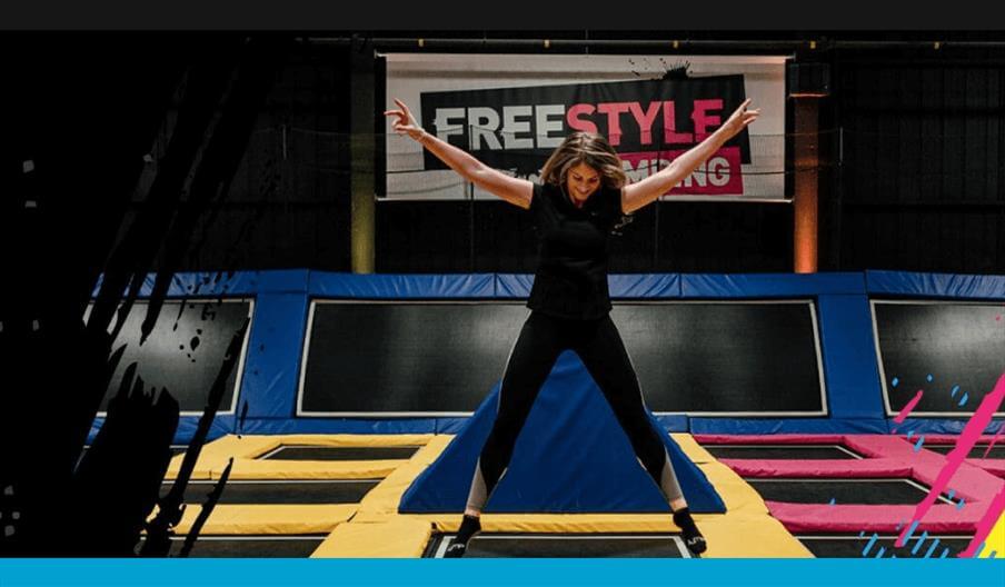 A person jumping and smiling on a large black trampoline at Jump Street
